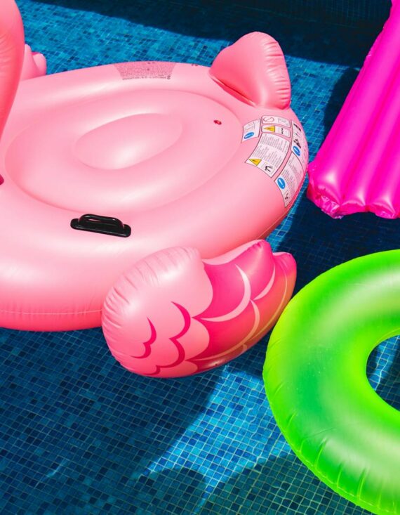 Bright inflatable flamingo and rings floating in a sunny pool.