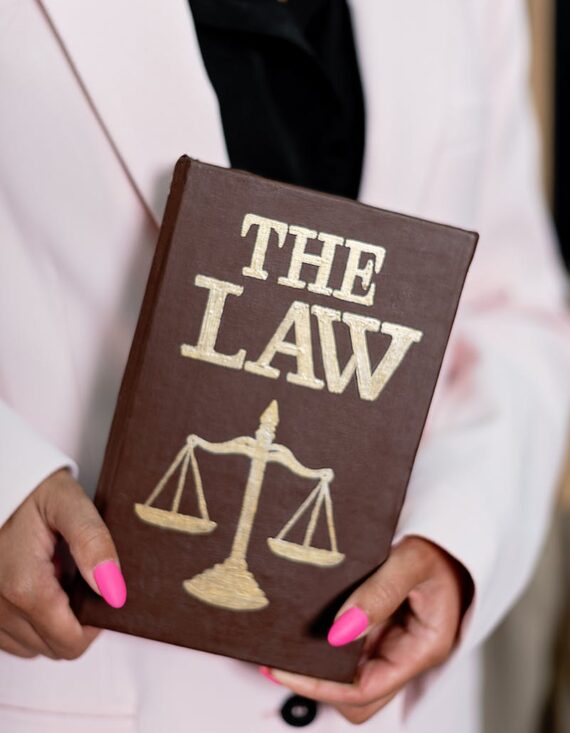 Close-up of a woman holding a law book with scales of justice, emphasizing legal themes.